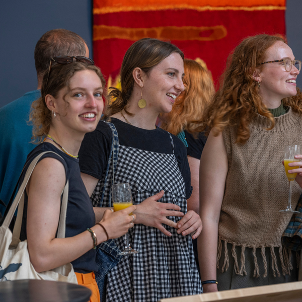 Group of attendees of an event at Dovecot Studios enjoy a drink on the balcony of the main exhibition space.