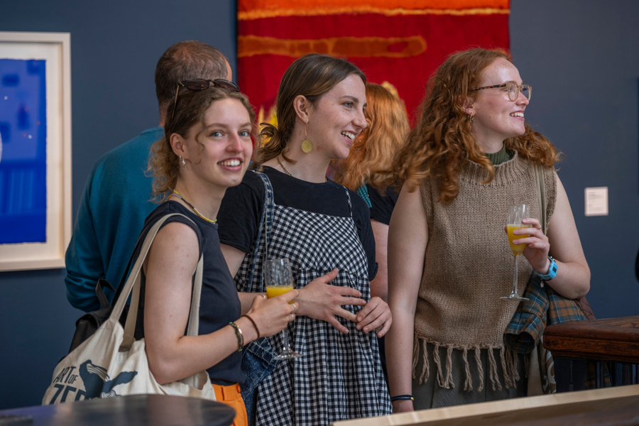 Group of attendees of an event at Dovecot Studios enjoy a drink on the balcony of the main exhibition space.